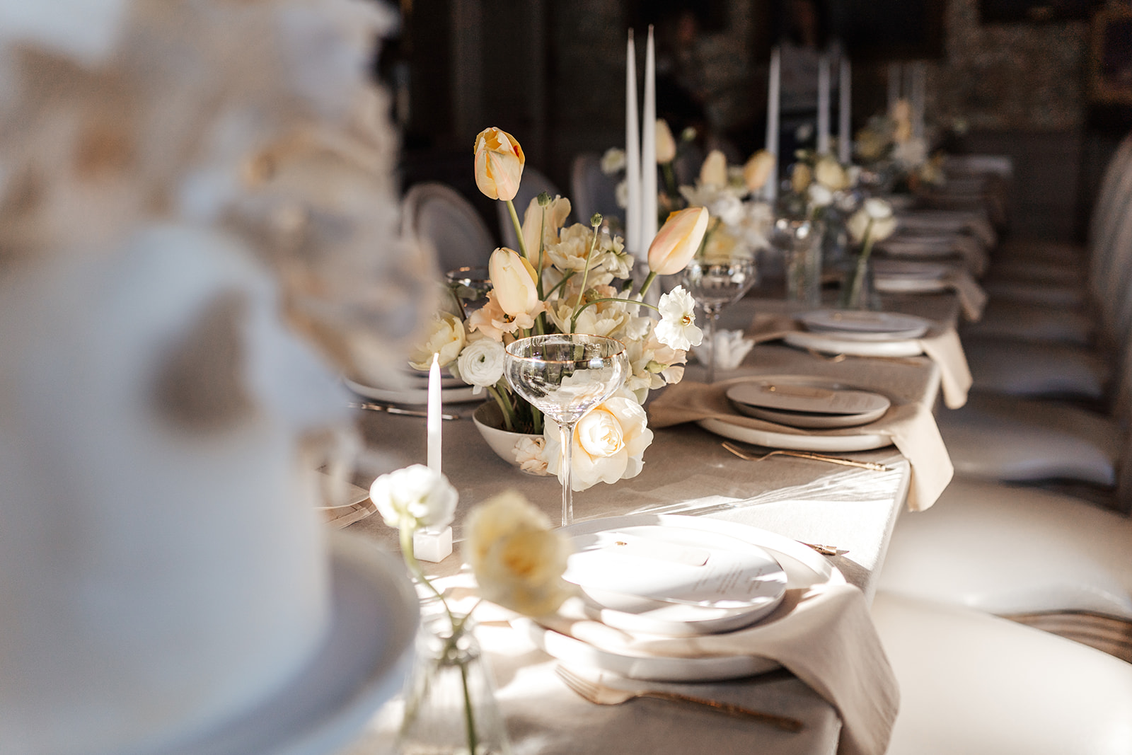 A wedding reception with long tables, place settings, flowers and candles, set up in a wooden venue.