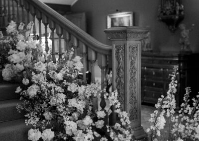 a black and white image of wedding floristry on a staircase at Hedsor wedding venue