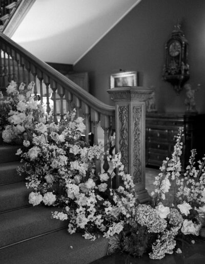 a black and white image of wedding floristry on a staircase at Hedsor wedding venue