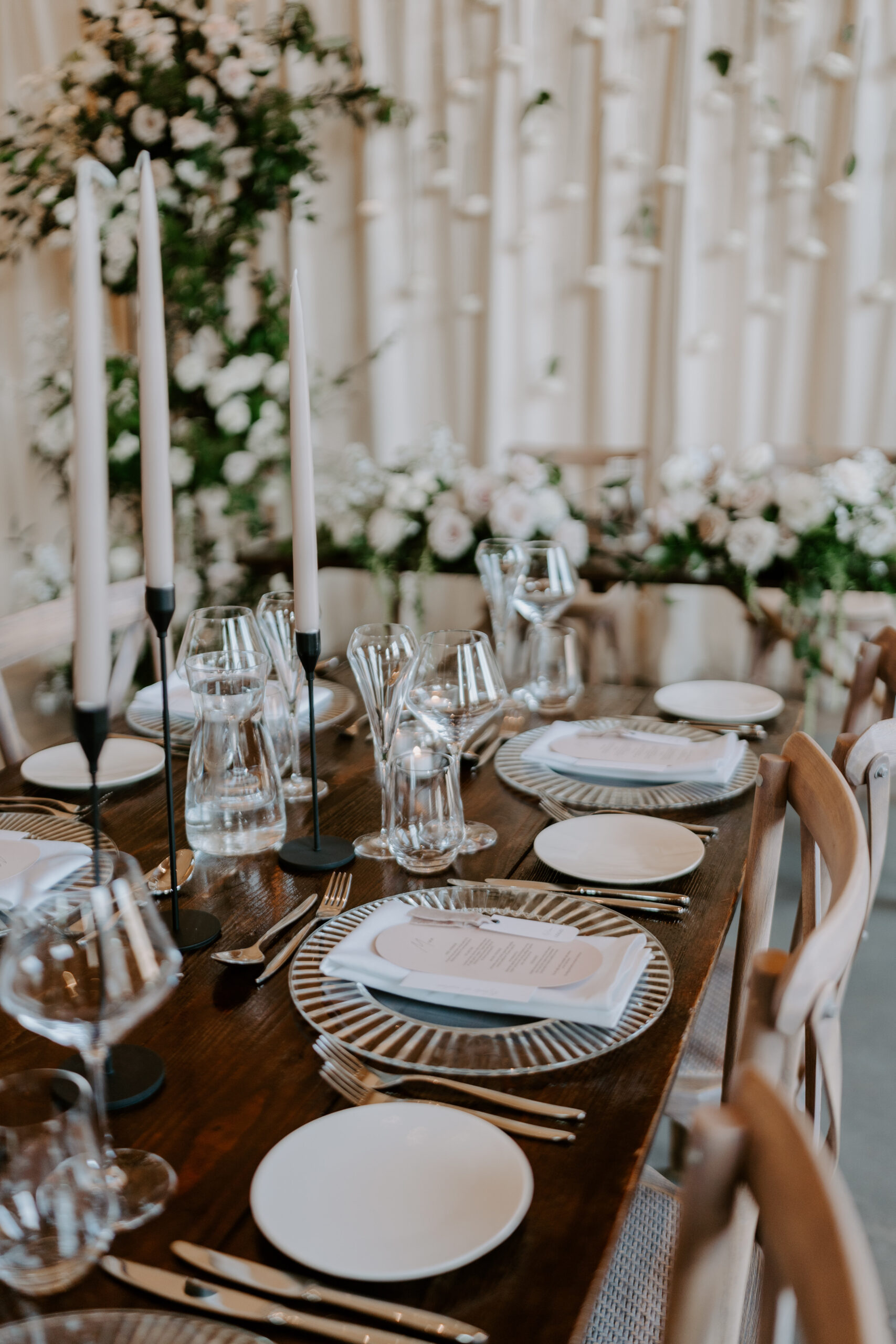 A beautifully styled wedding table set with white plates and candles.