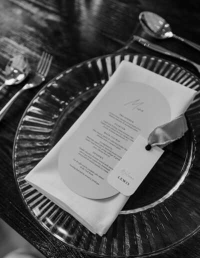 A black and white photo of a wedding place setting with silverware.