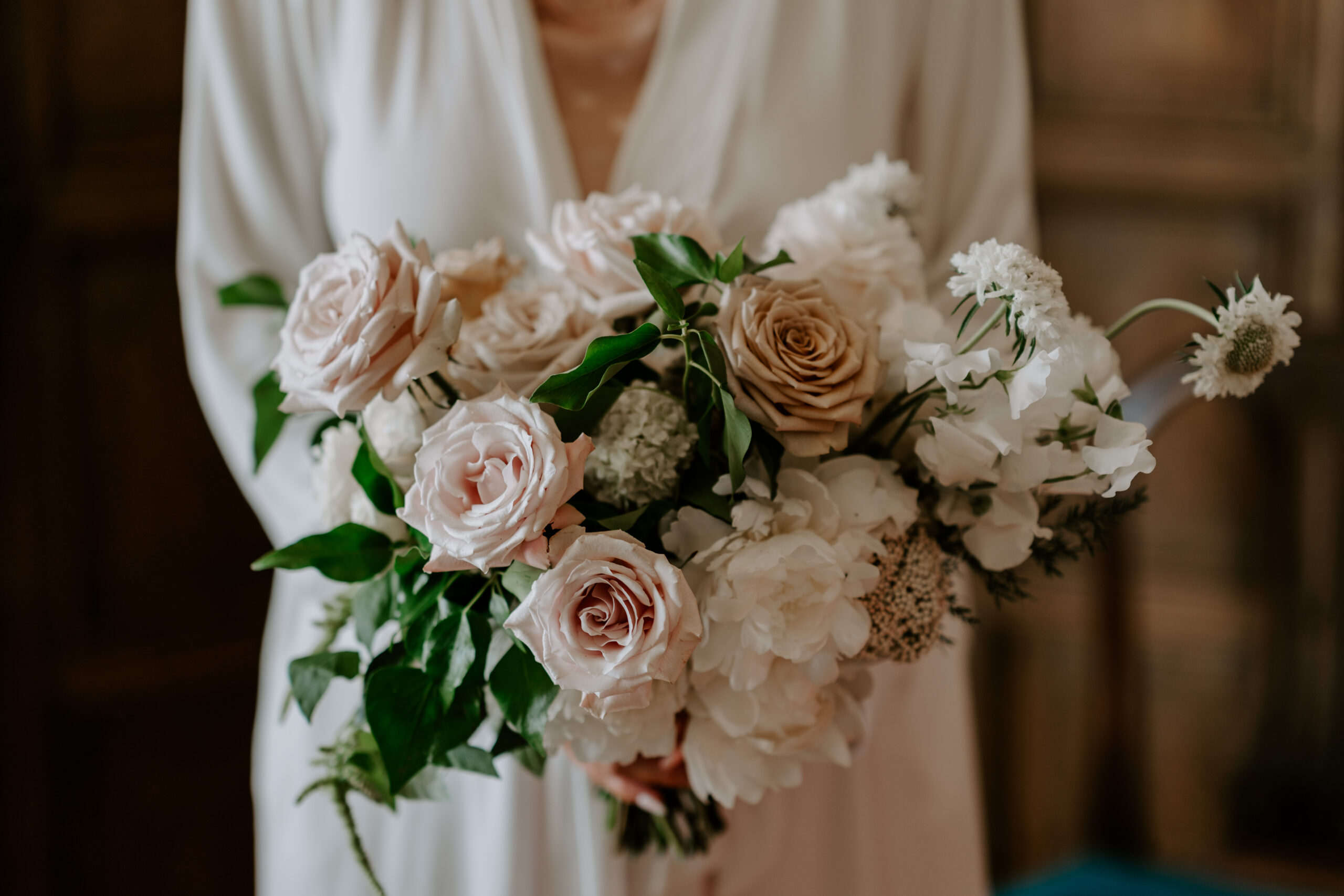 A bride holding a bouquet of pink and white flowers.