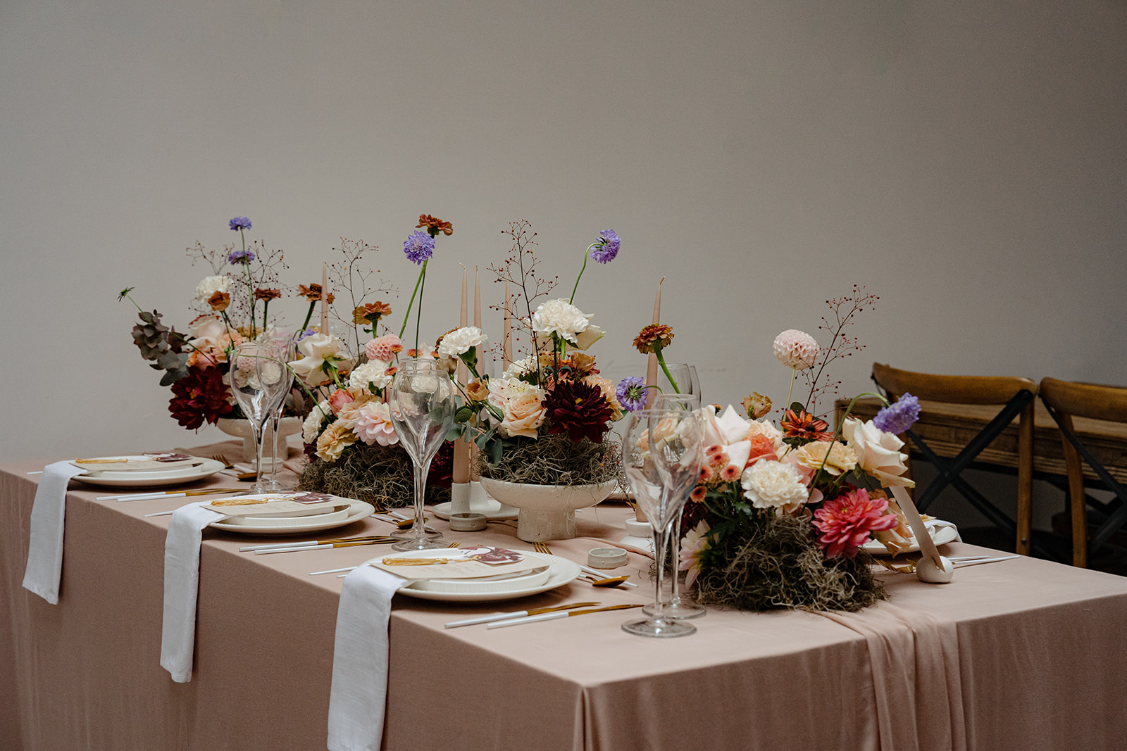 A large bouquet of pink and white roses and greenery sitting behind a row of chairs for a barn wedding.