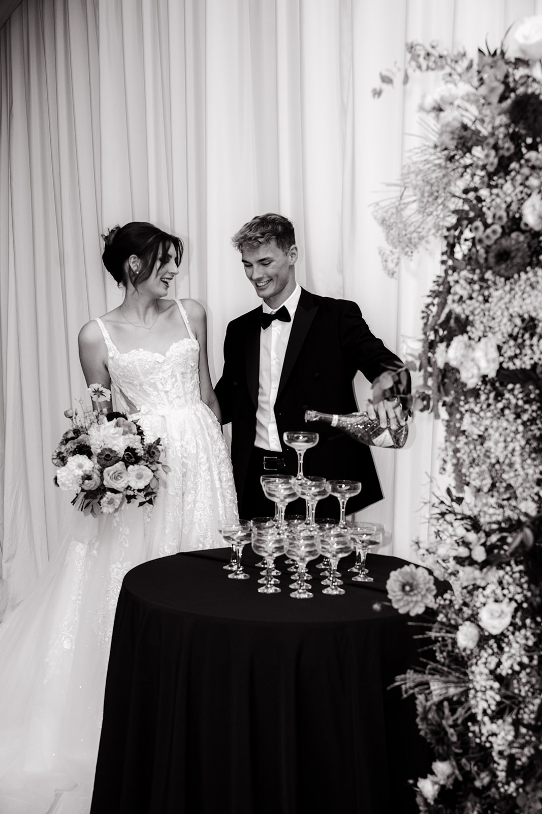 A black and white photo of a table plan with flowers in front of it, showcasing elegant wedding styling.