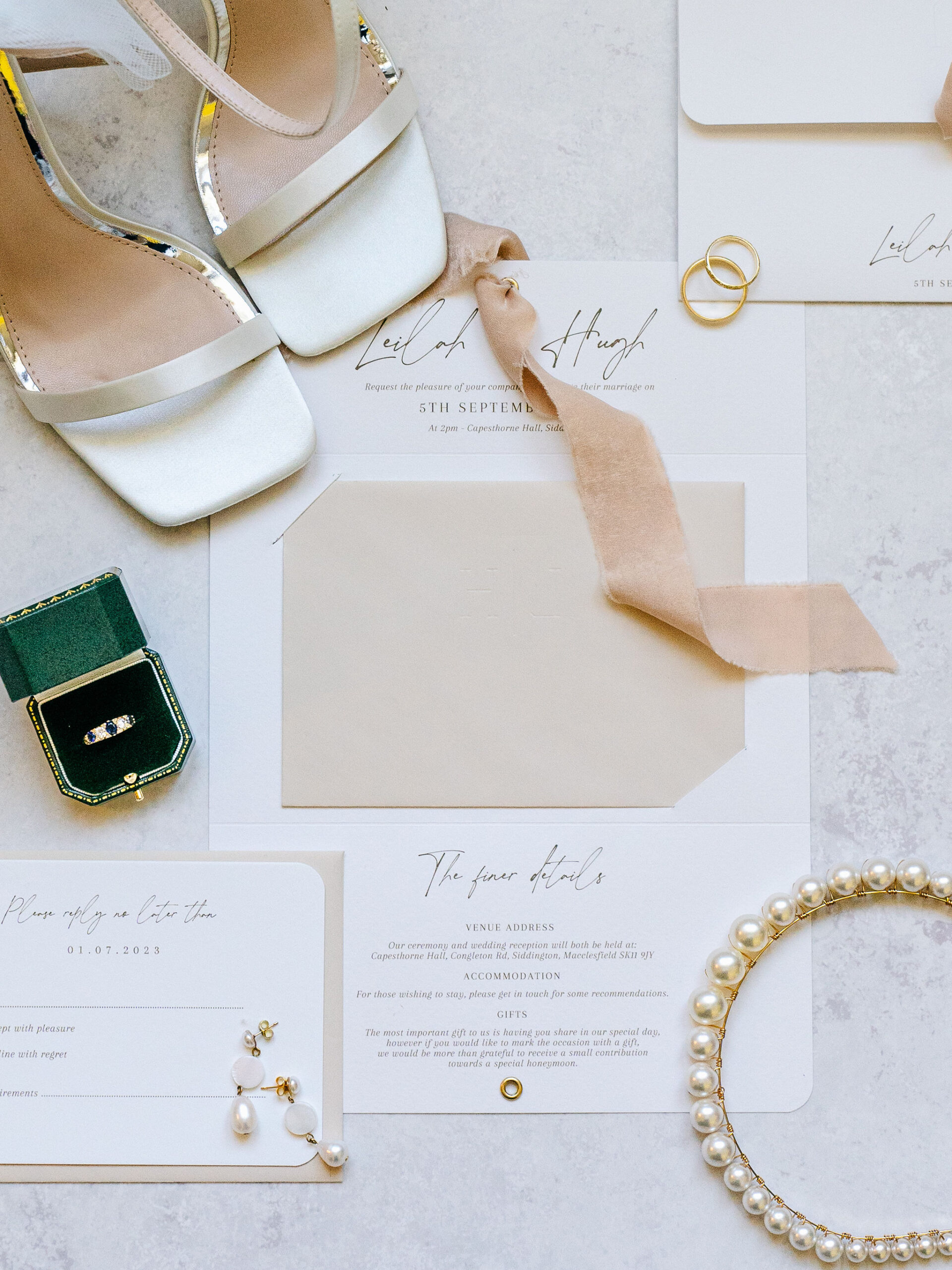 A wedding invitation suite flat lay with bridal accessories and shoes for a photo shoot at Capesthorne Hall.