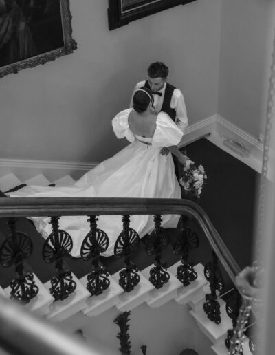 A black and white image of a bride & groom on a staircase at Hedsor House wedding venue