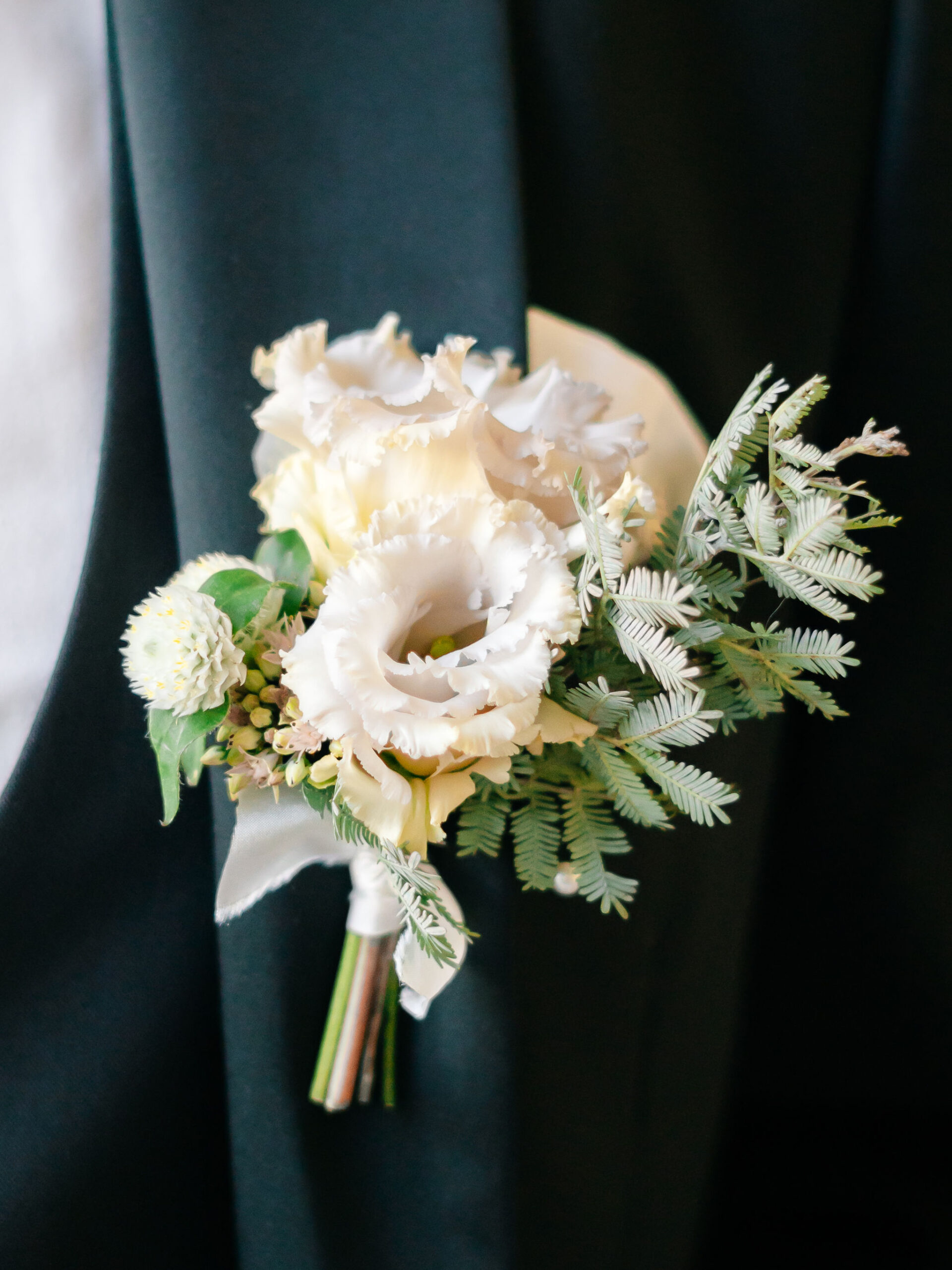 A colour images of a grooms floral button hole  in pale pinks and sage green for a photo shoot at Capesthorne Hall in Cheshire. 