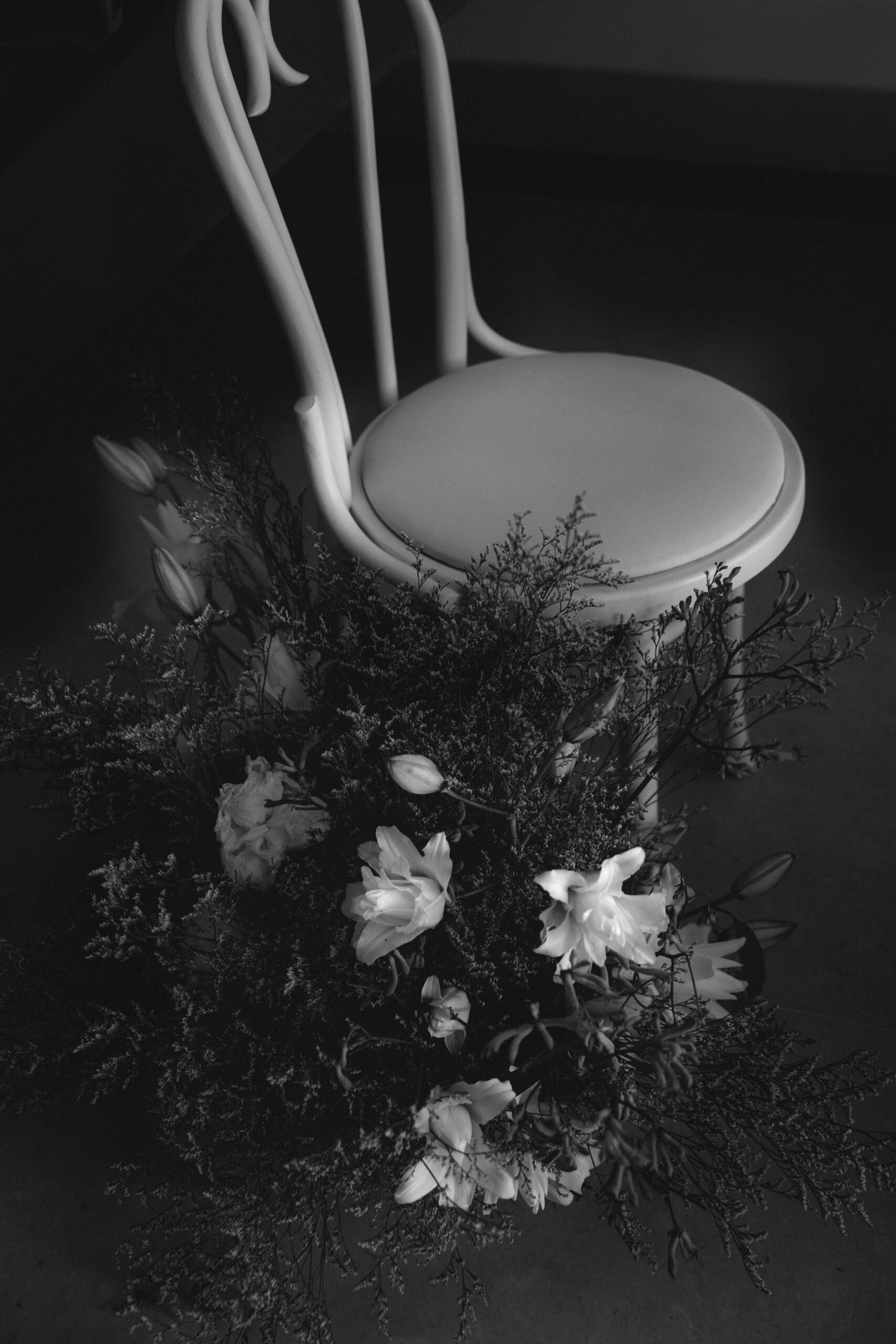 CHESHIRE-WEDDING-FLORISTRY-AND-STYLING A black and white image from a wedding ceremony displaying aisle florals and a beautiful, elegant chair.