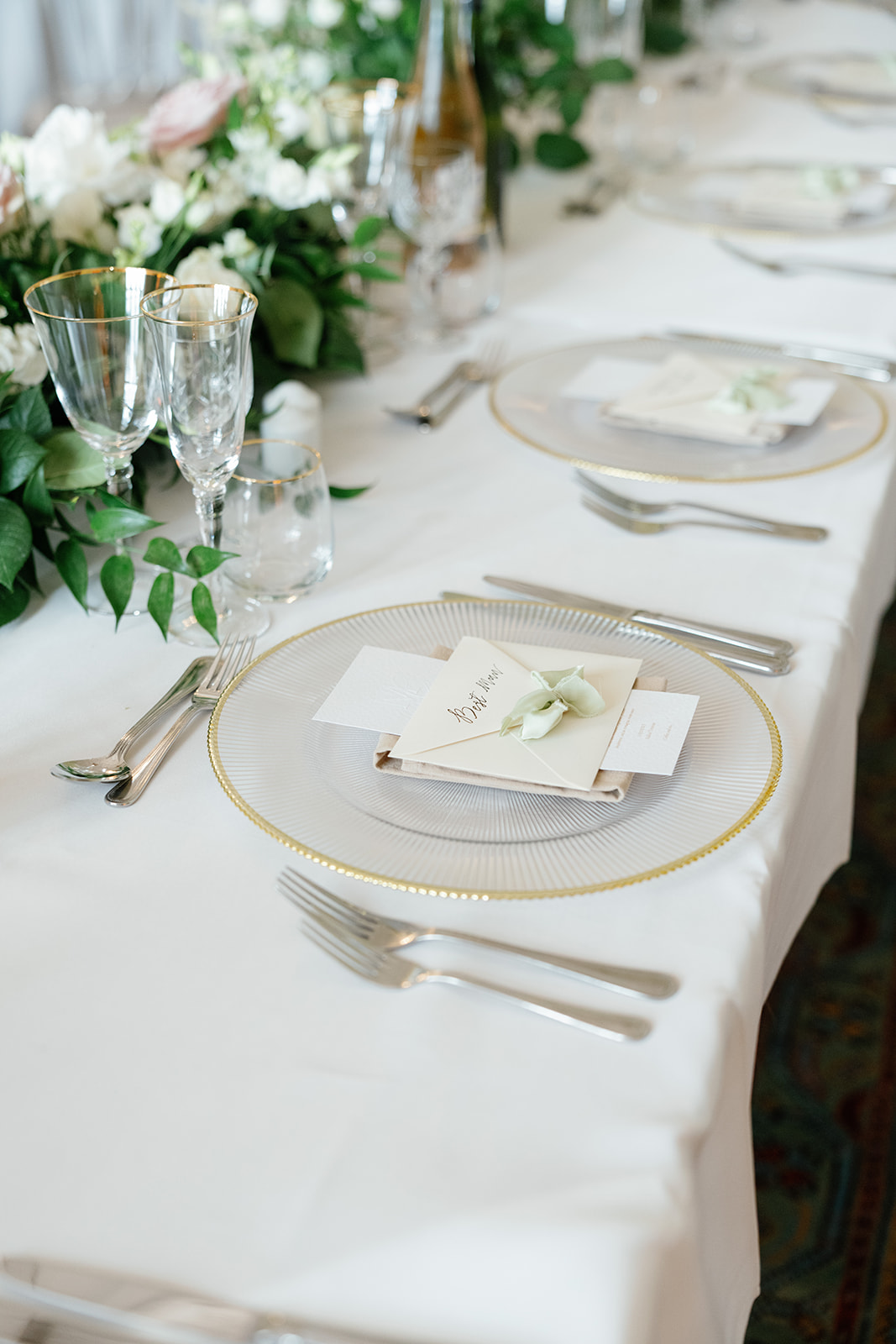 Madeleine & Chris A colour image of a wedding top table with gold rim charger plates and elegant timeless wedding floristry.