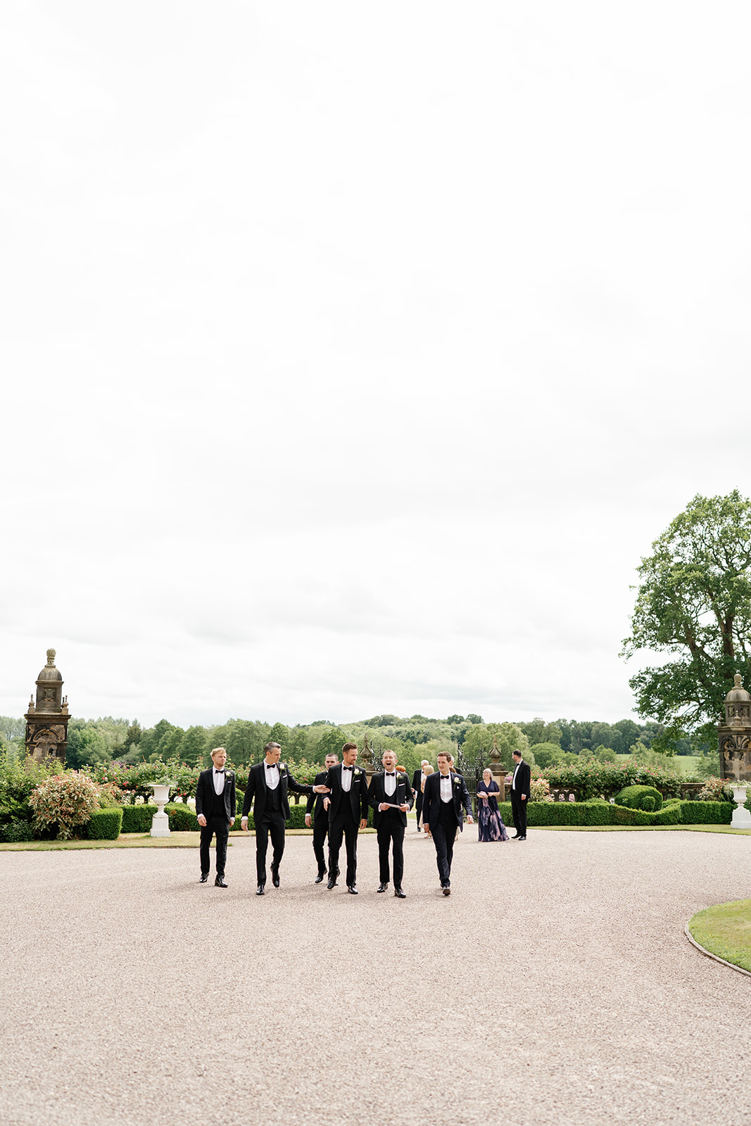 Madeleine & Chris A colour image of a groom and his groomsmen walking to Capesthorne Hall in Cheshire.