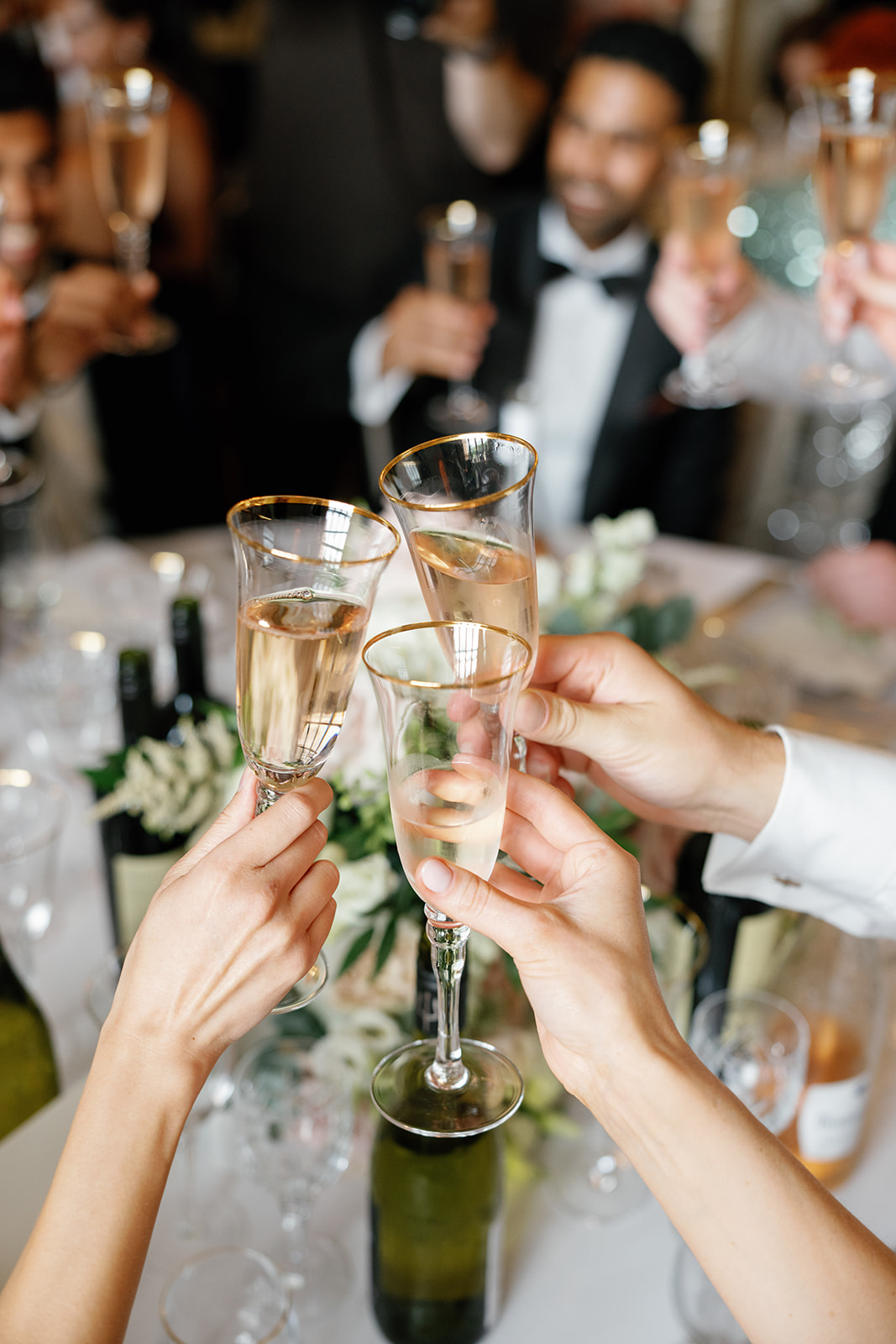 Madeleine & Chris A colour image of guests raising a toast with gold rim wine glasses at an elegant wedding planned by Soiree studio.