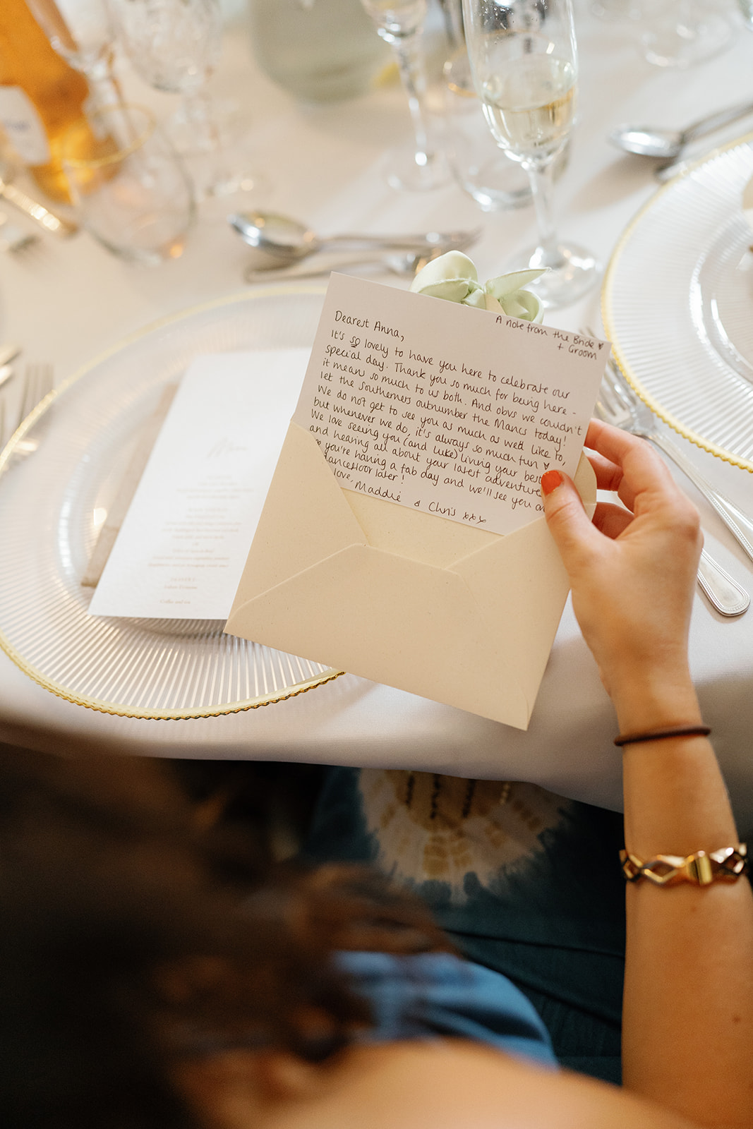 Madeleine & Chris A colour image of a wedding guest opening up their hand written note as a wedding favour at the wedding breakfast.