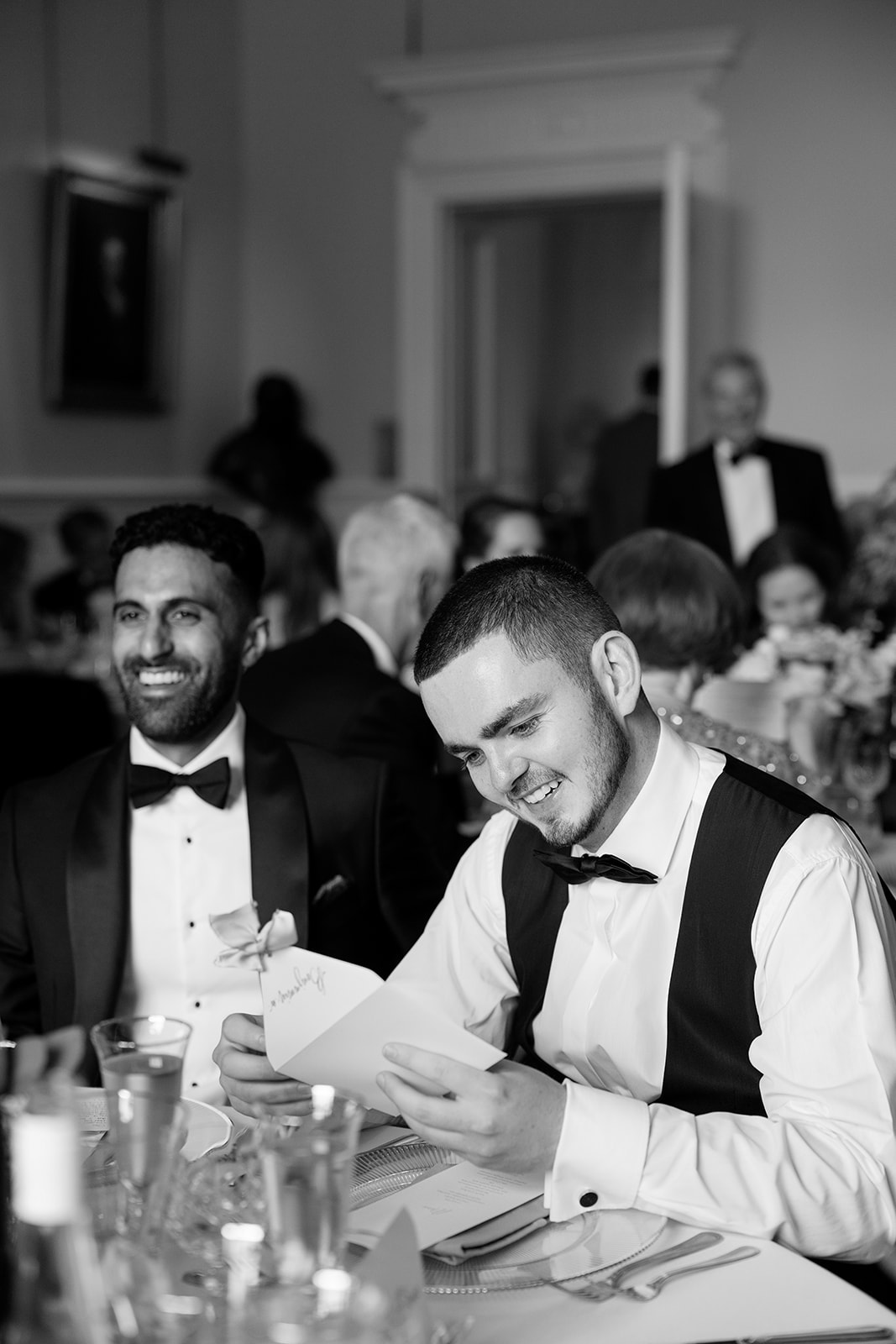 Madeleine & Chris A black and white image of a wedding guest enjoying reading a personal note from the bride and groom at the wedding breakfast.