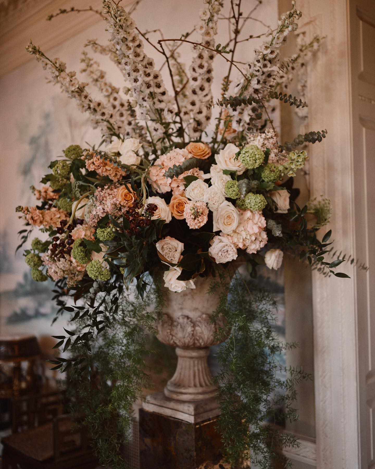 A colour image of beautiful autumn wedding flowers in an urn at the entrance of a wedding ceremony at Hedsor House.