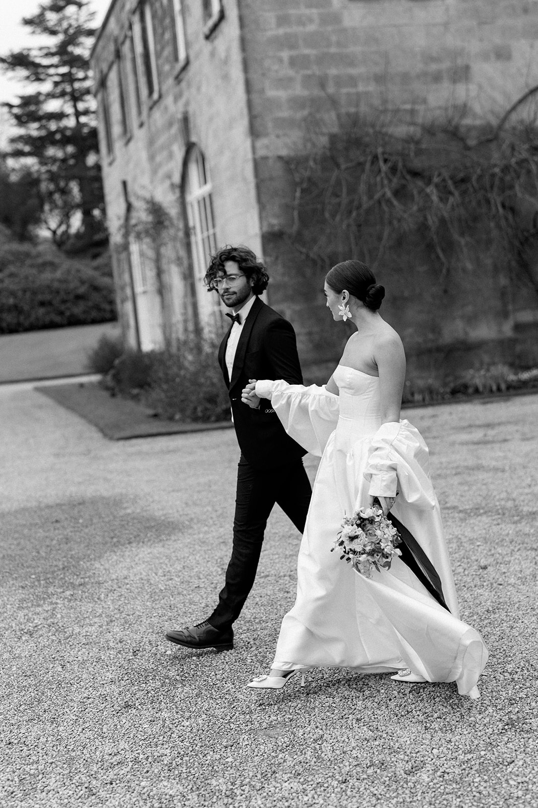 Birdsall House A black and white image of a couple leaving the church after their wedding ceremony in the Cotswolds, planned by Soiree Studio.