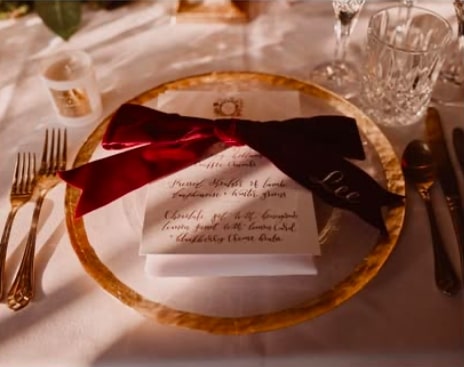  colour image of a wedding place setting with red velvet bow and calligraphy menu by Soiree Studio at Hedsor House.