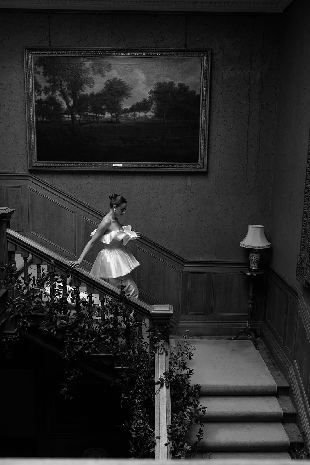 Birdsall House A black and white image of a bride walking down the stairs in a beautiful editorial style wedding dress at Birdsall House in Yorkshire.