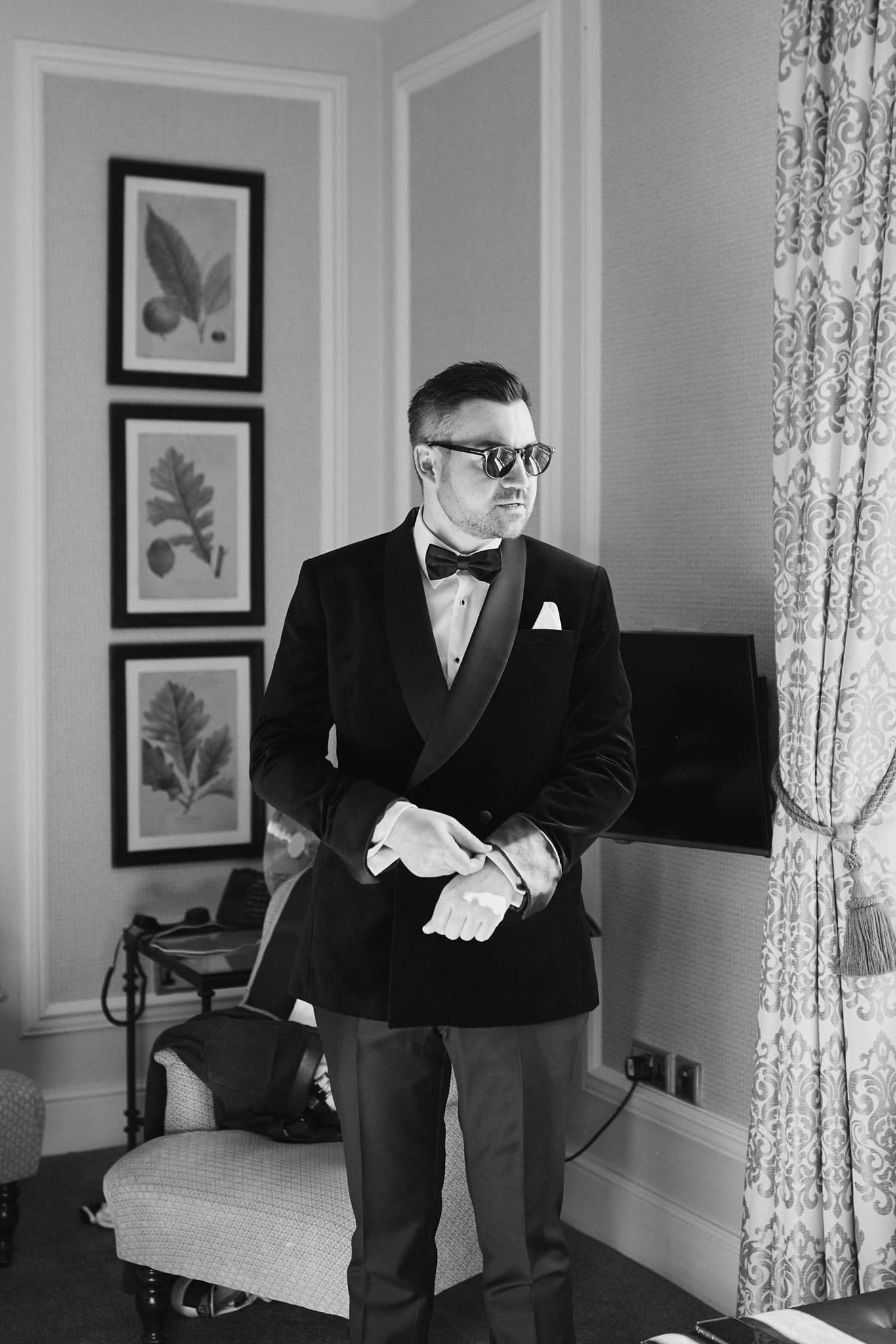 A black and white image of a groom in black tux at Hedsor House at the beginning of his wedding ceremony.