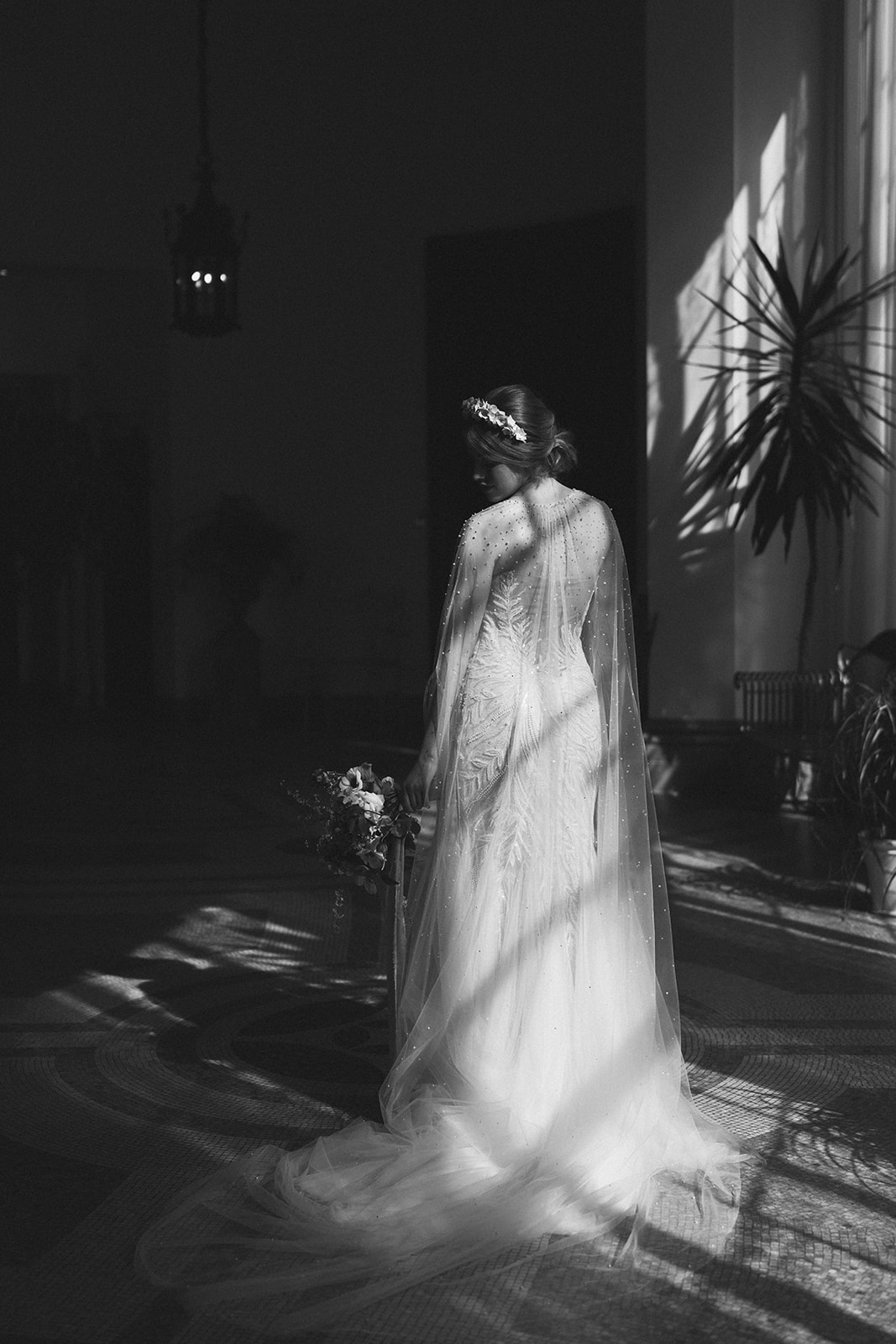 A black and white image of a bride standing in the sunshine looking down at Hawkstone Hall Shropshire.
