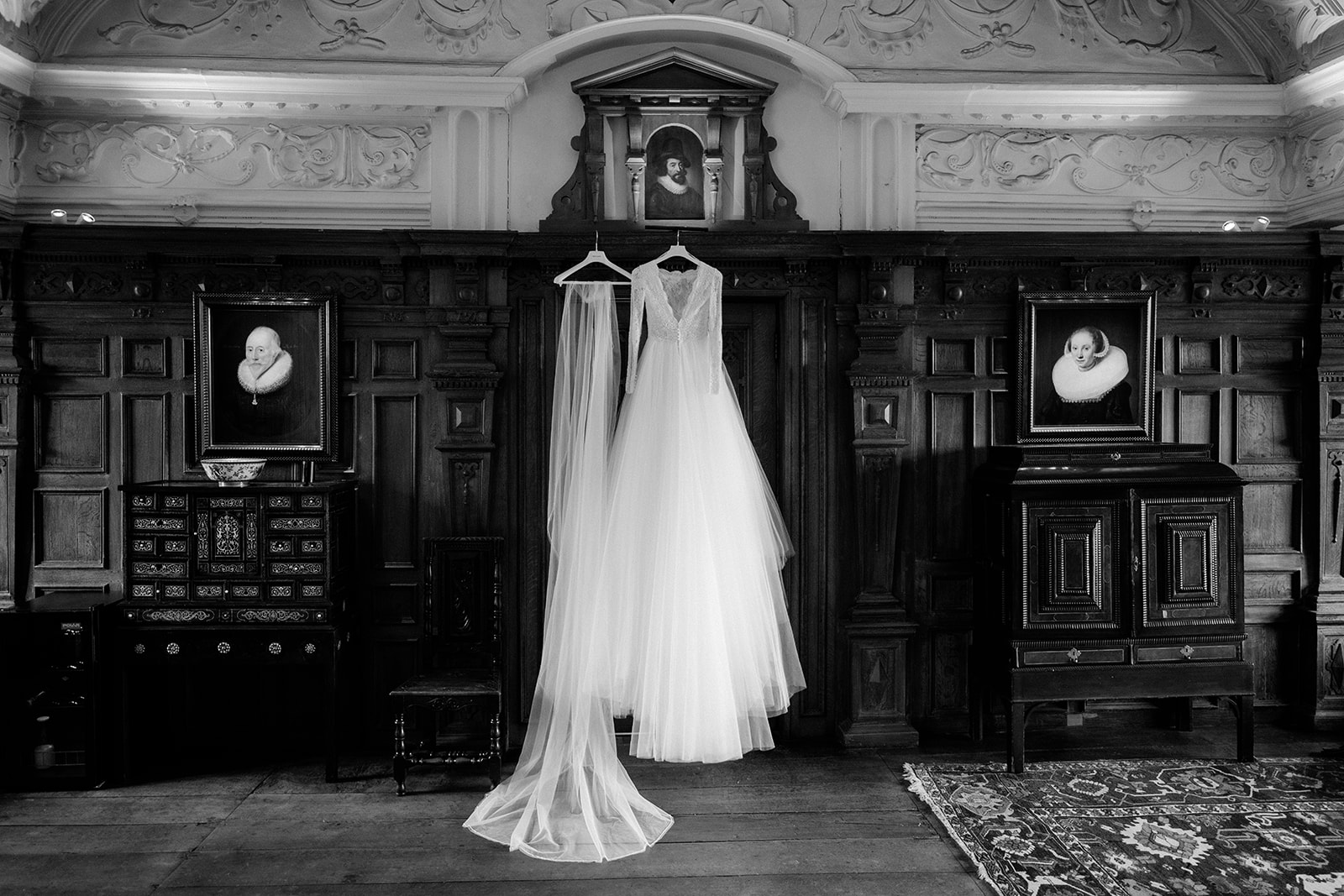 Amy and Jack A black and white image of a brides dress and veil hanging on the door of the bridal suite at Dorfold Hall in Cheshire.