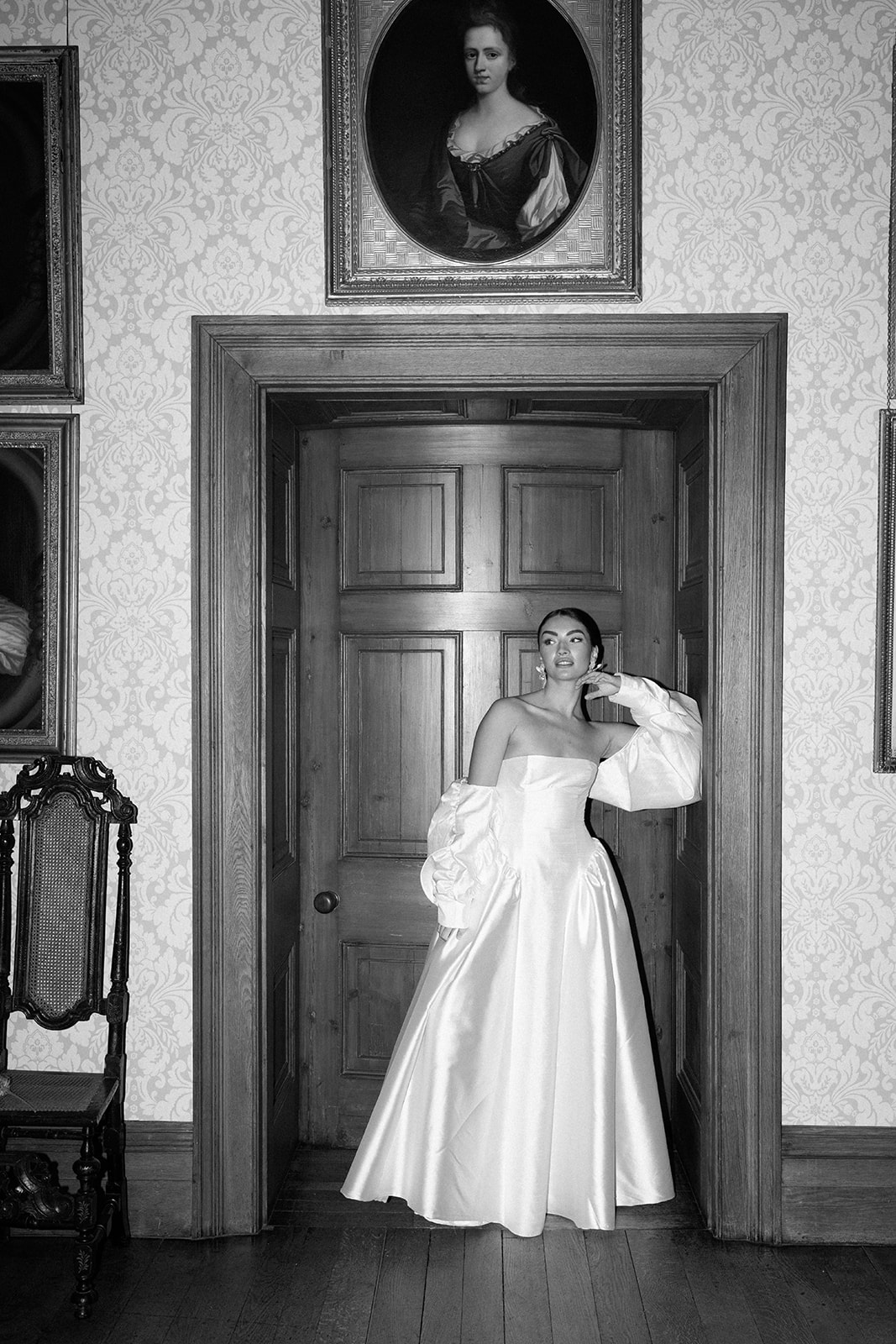 Birdsall House A black and white image of a bride standing in the doorway in her dress at Birdsall House in Yorkshire.