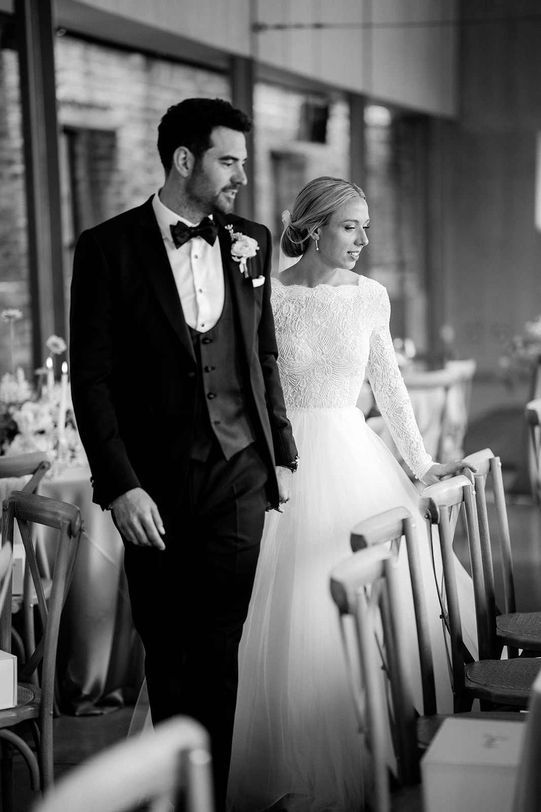 Amy and Jack A black and white image of a bride and groom looking at their table styling before the guests arrive for dinner at a wedding planned at Dorfold Hall in Cheshire.
