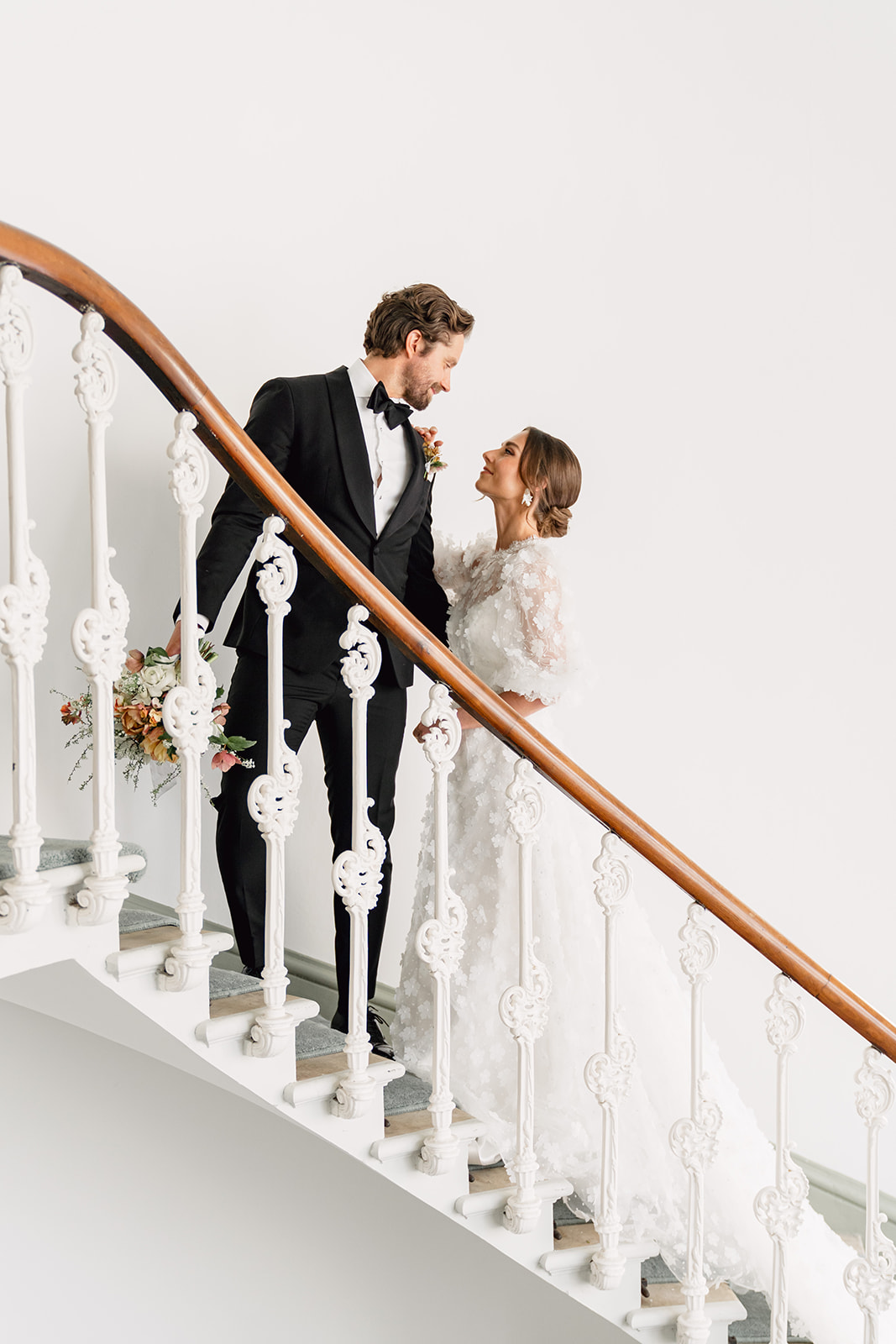 A colour image of a bride and groom looking at each other lovingly on the stairs at Hawkstone Hall Shropshire.