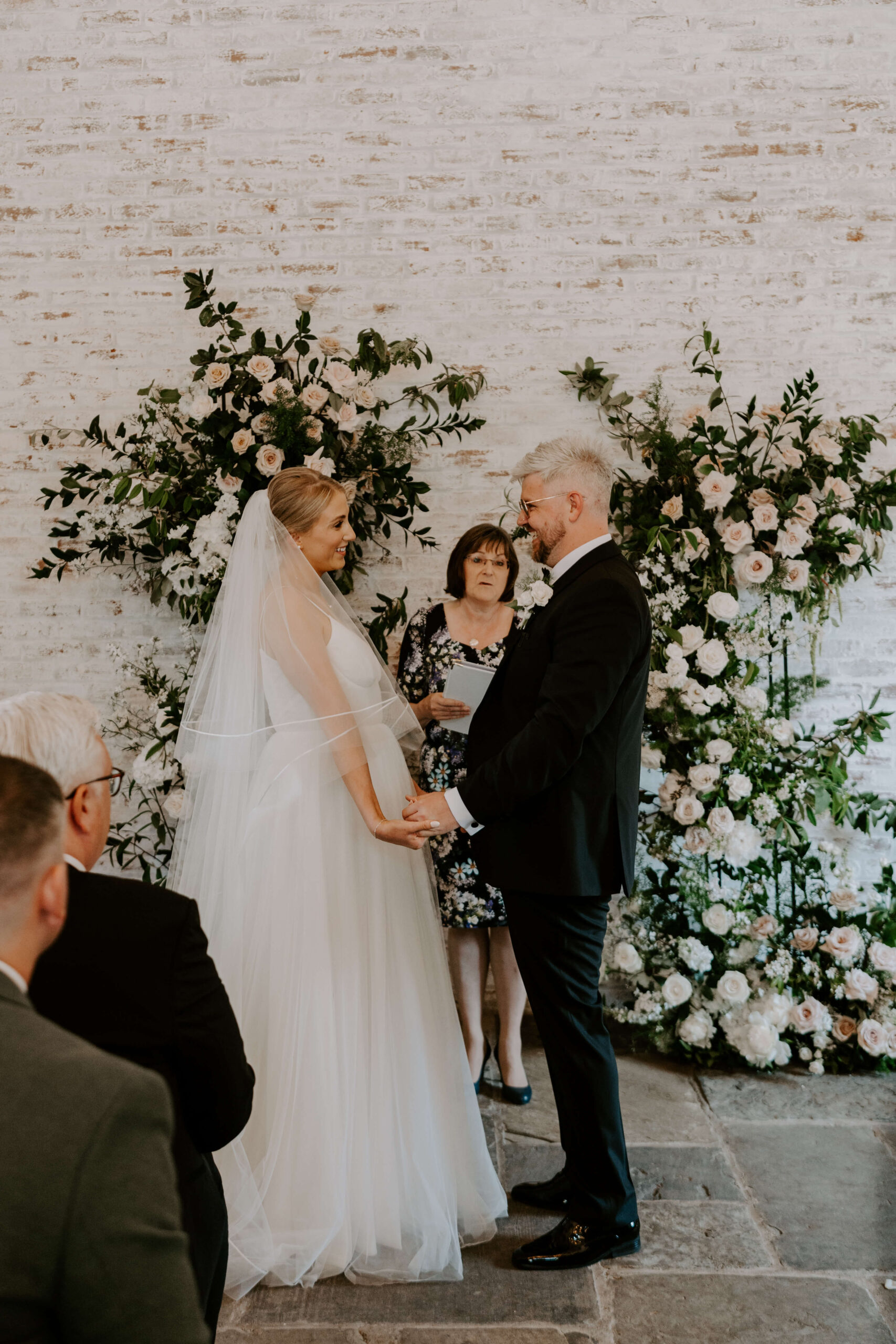 bride-and-groom-wedding-ceremony-at-dorfold-hall-cheshire A bride and groom in front of a beautiful spring floral arch at their wedding ceremony at Dorfold Hall in Cheshire.