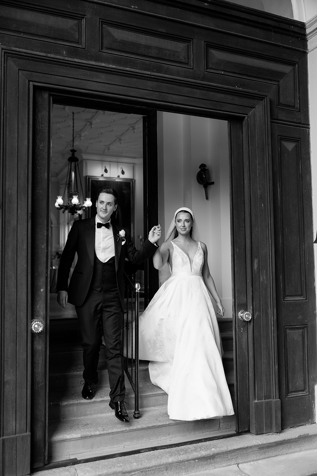 Madeleine & Chris A bride and groom exiting the large doors at Capesthorne Hall Cheshire after their wedding ceremony.