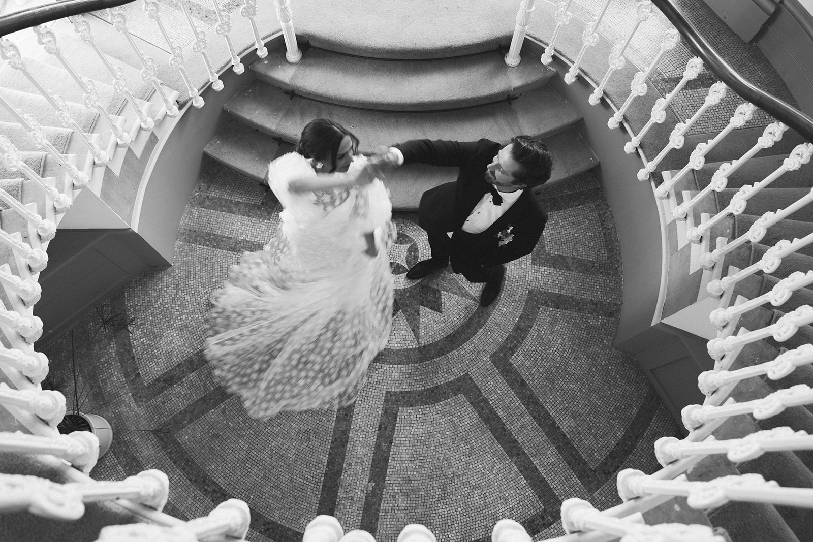 A black and white image of a bride and groom dancing at the bottom of the stairs at Hawkstone Hall Shropshire.