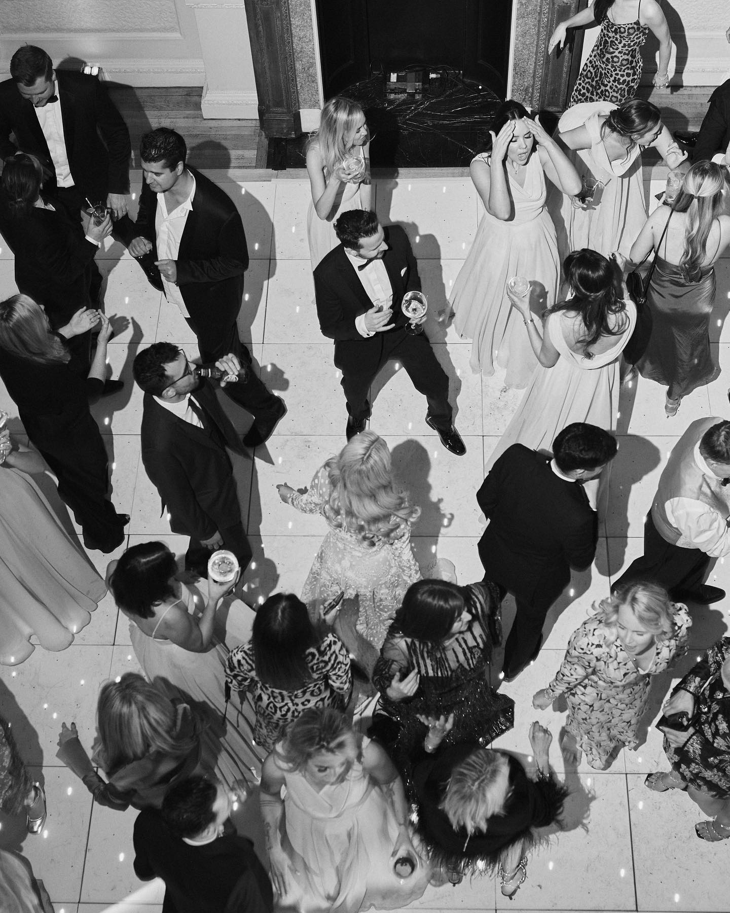 A black and white image of a birds eye view of wedding guests dancing at a wedding reception at Hampton Manor.
