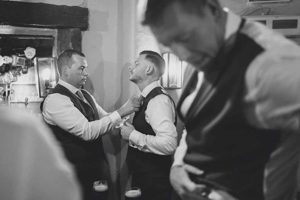 groom-prep-at-combermere-abbey-in-shropshire A black and white image of a groom and groomsmen getting ready for a wedding at a marquee in Shropshire planned by soiree studio.