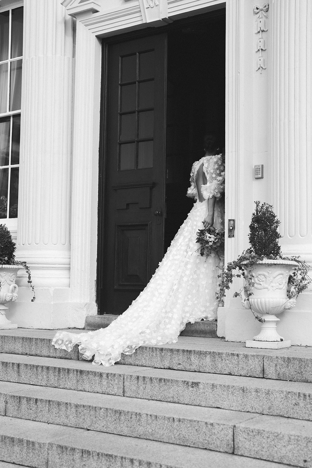 A black and white image of a bride entering the doors of Hawkstone Hall wedding venue in Shrewsbury.