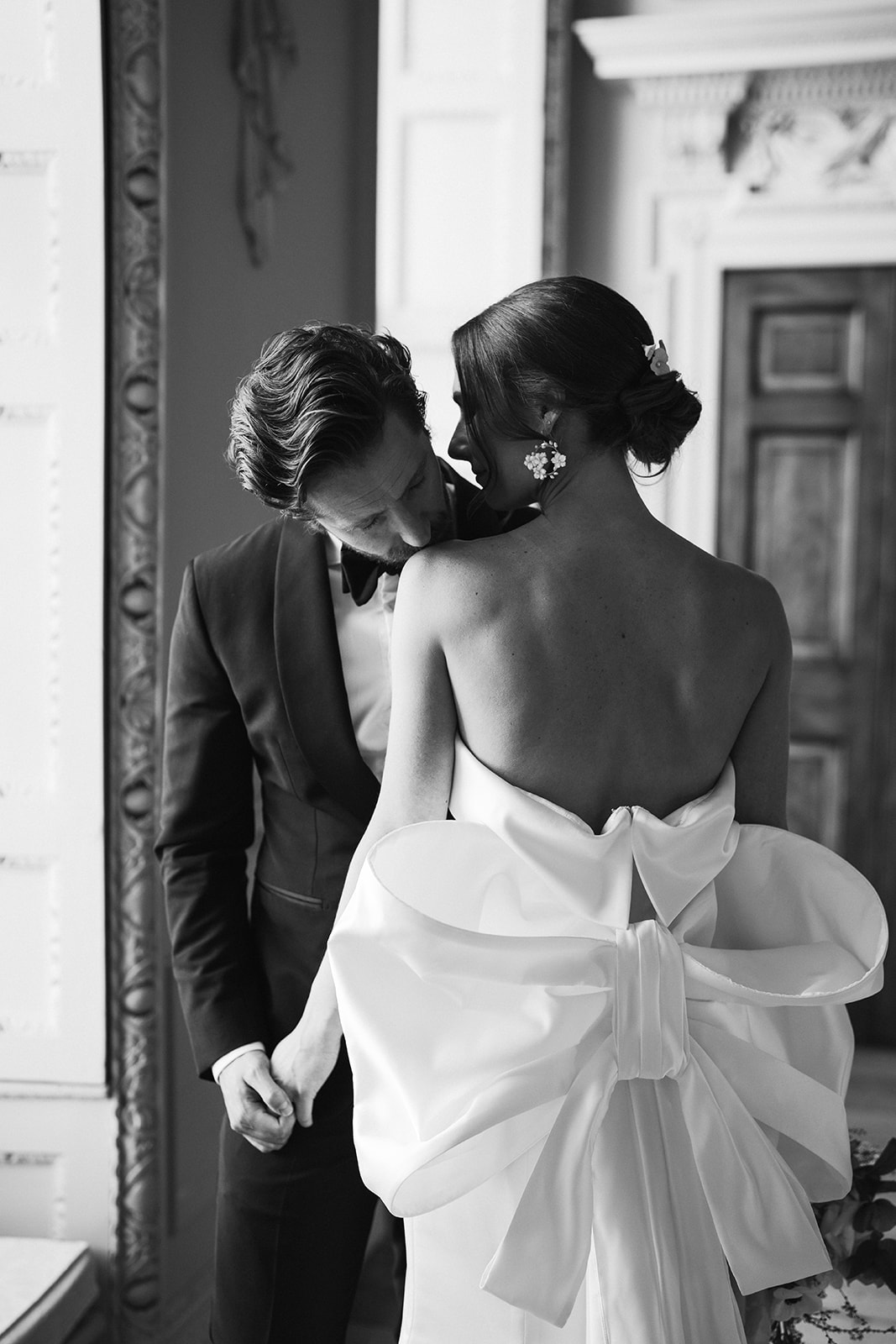 a black and white image of a A bride and groom kissing in front of the grand windows at Hawkstone Hall in Shrewsbury.