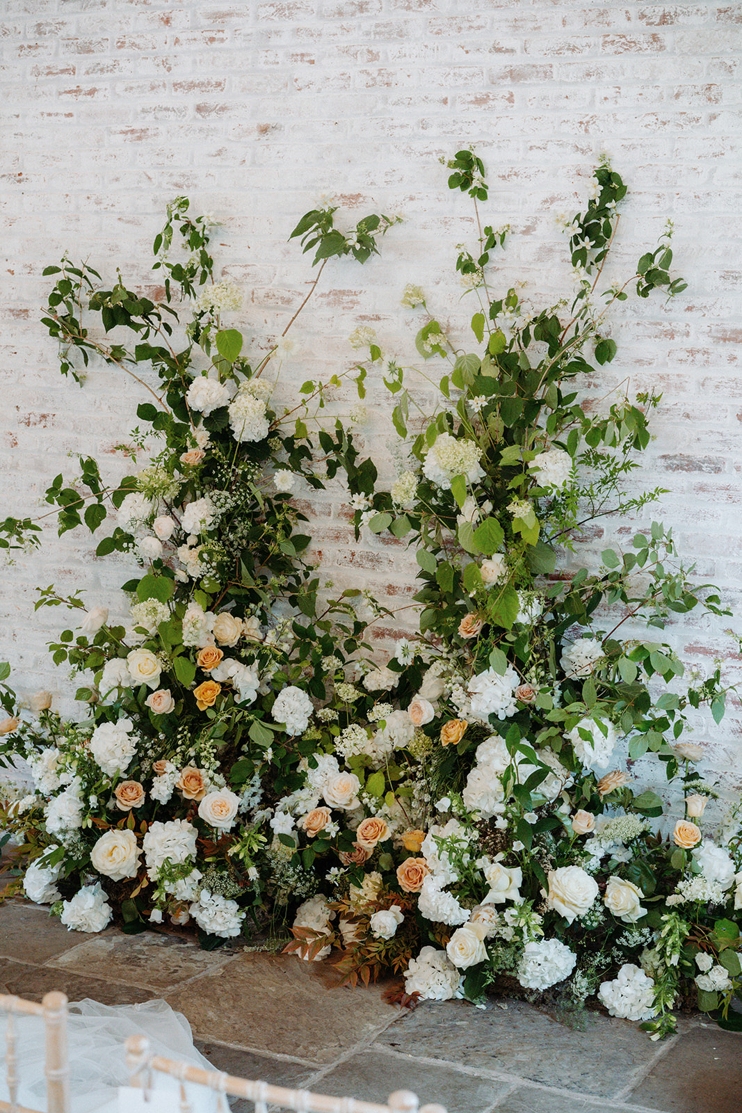 Amy and Jack A wedding ceremony broken arch of spring flowers and foliage by Sassflower at Dorfold Hall Cheshire.