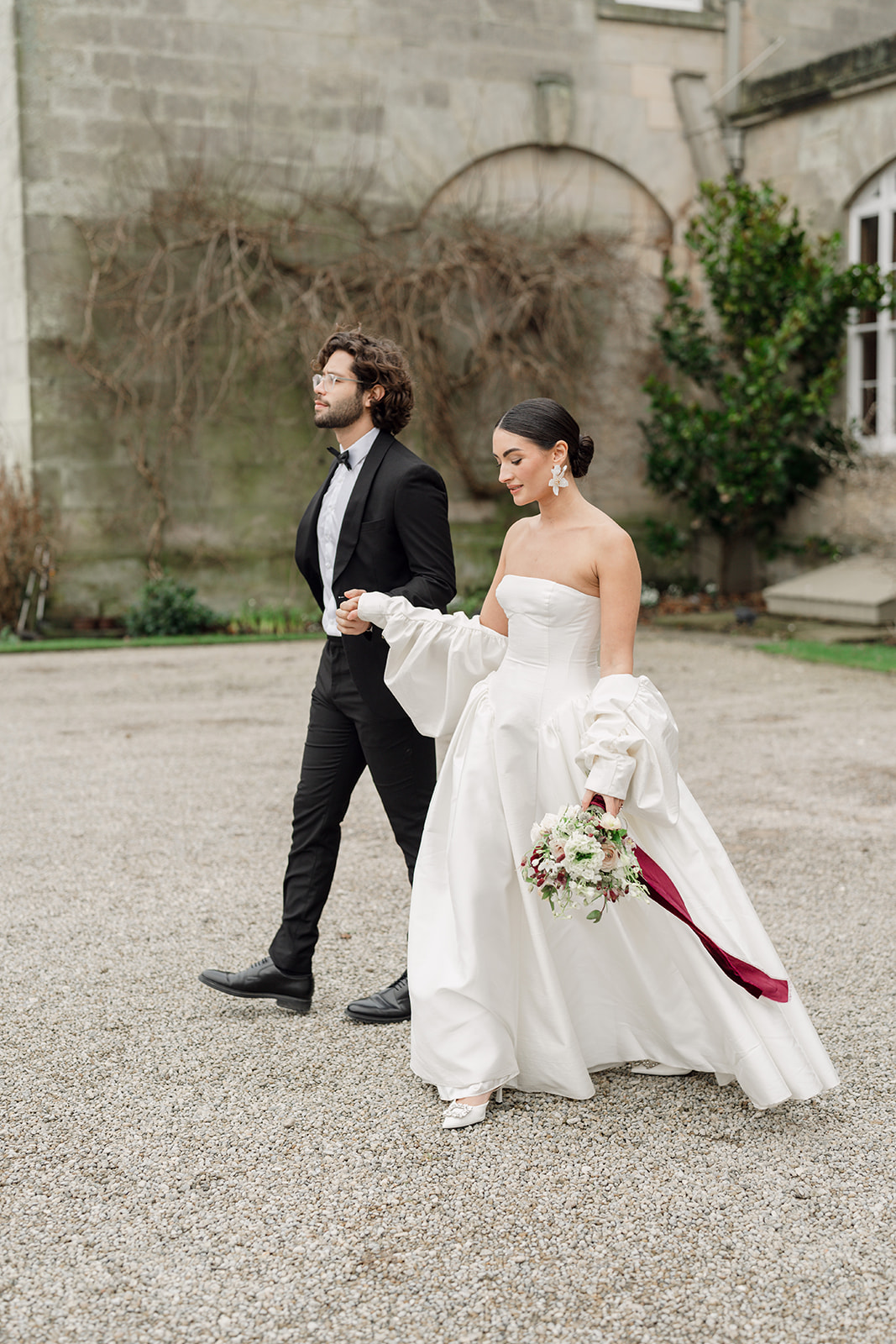 A colour image of a bride and groom walking out of Birdsall House after their wedding ceremony planned by Soiree Studio Wedding Planning and design.