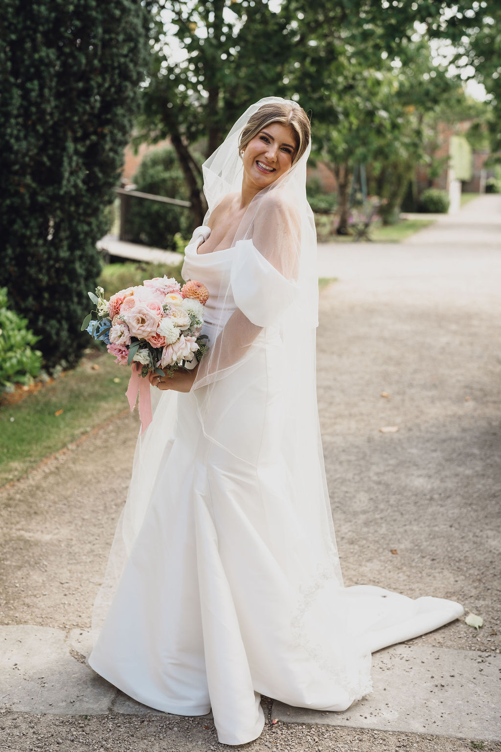 private-estate-marquee-wedding-planning-shropshire A colour image of a beautiful summer bride on her wedding day holding a bright summer wedding bouquet at her marquee wedding planned by Soiree studio.