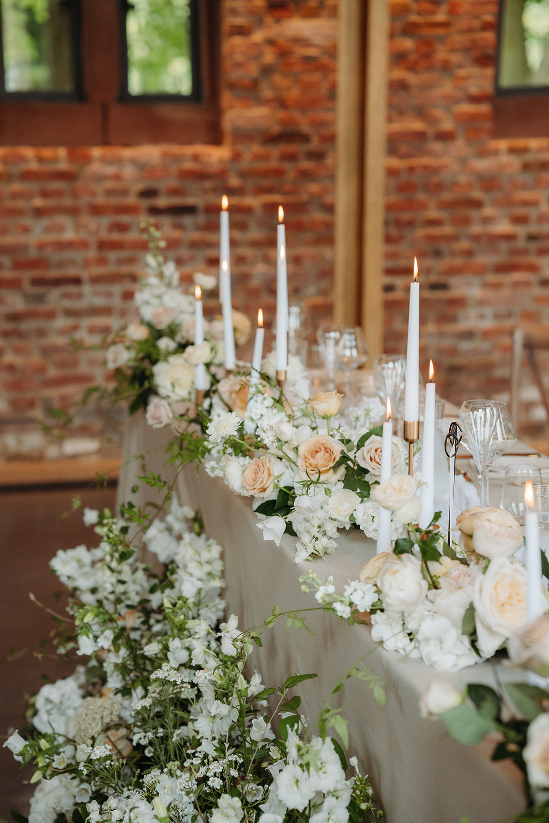 Amy and Jack A colour image of beautiful spring flowers and white tapered candles on the top table of a wedding planned at Dorfold Hall in Cheshire.