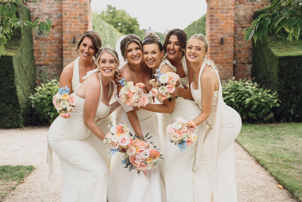 summer-marquee-wedding-by-soiree-studio-wedding-planning-shropshire A colour image of a bride with her bridesmaids wearing butter yellow bridesmaid dresses with beautiful summer floral bouquets in pink and peach at a marquee wedding in Shropshire.