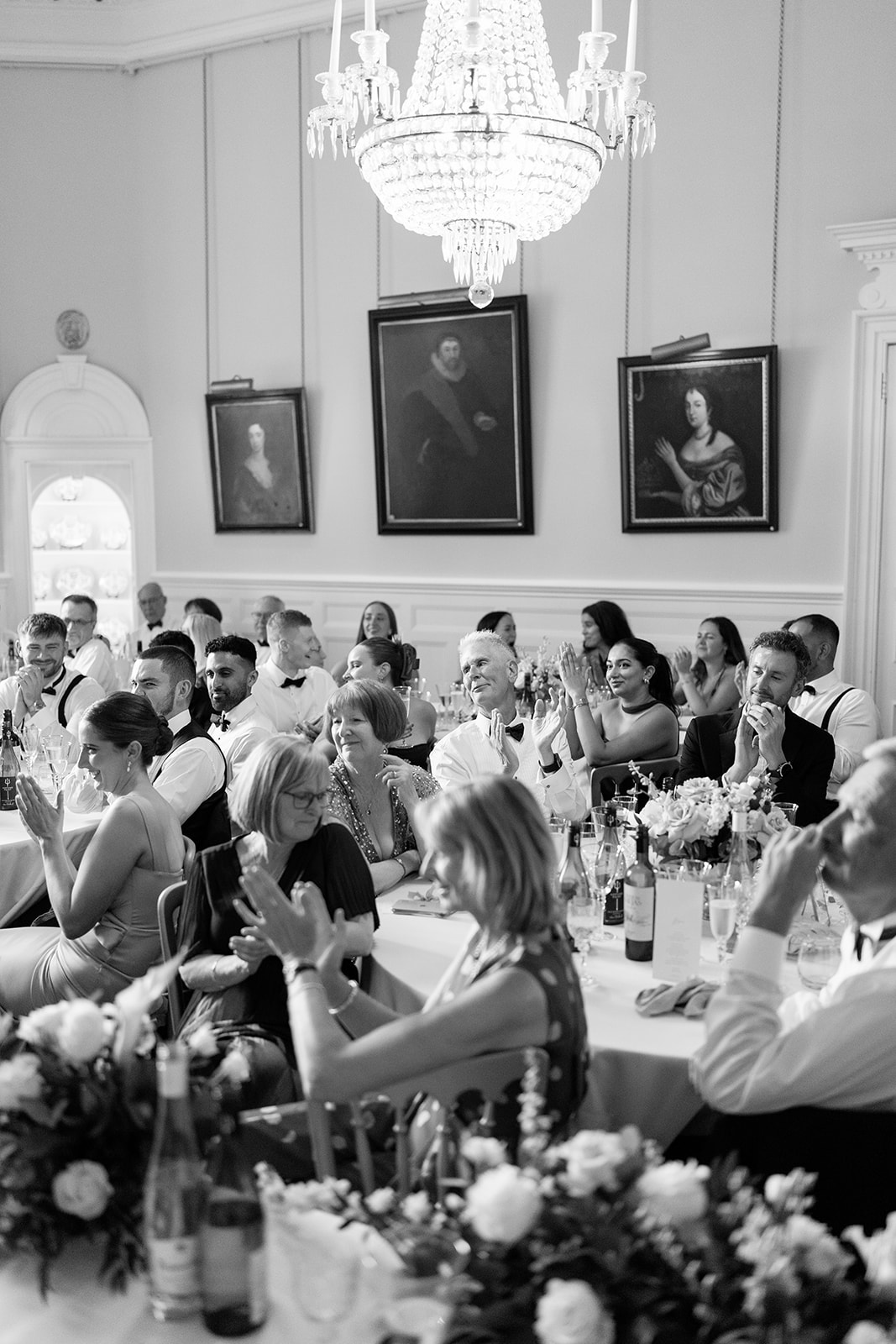 Madeleine & Chris A black and white image of a wedding breakfast room filled with friends and family.