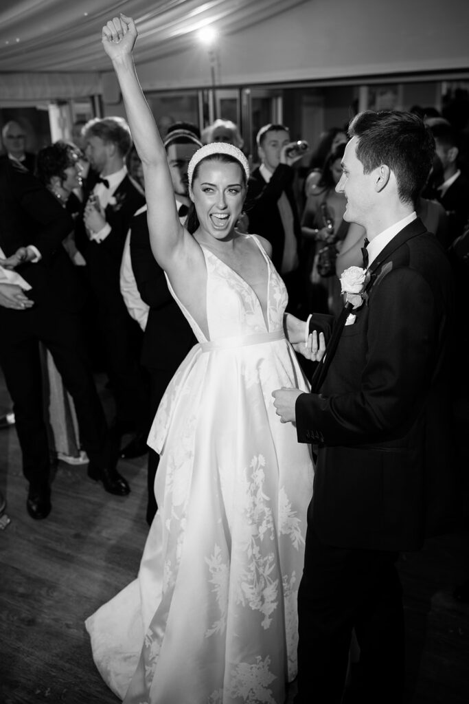 A black and white image of a bride having a great time dancing at her evening wedding reception planned by soiree studio in Cheshire.