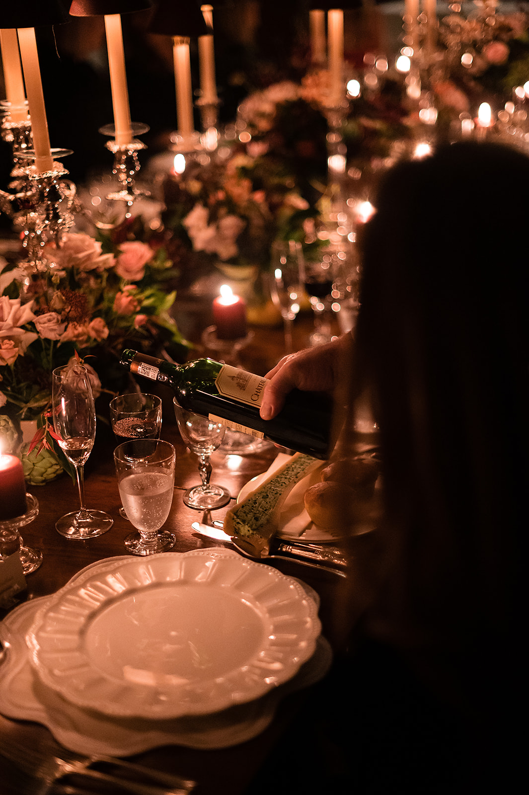 A black and white image of a bride and groom pouring champagne onto a champagne tower at their marquee wedding in the Cotswolds.