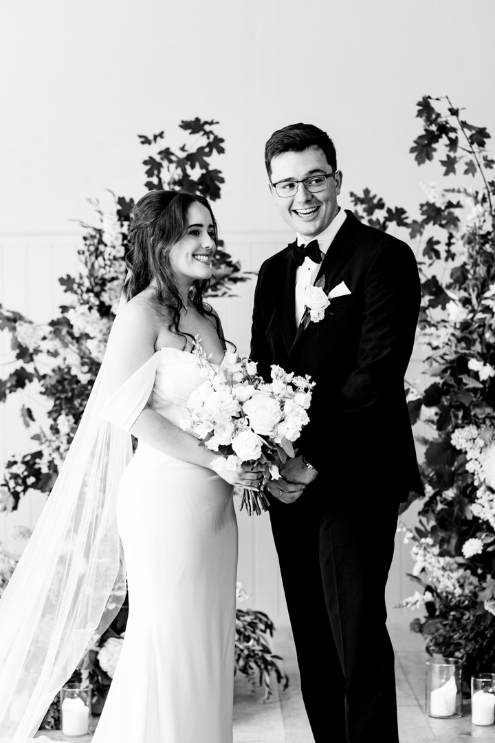 A black and white image go a bride and groom at their wedding ceremony planned by Soiree studio UK wedding planner at Hampton Manor. 
