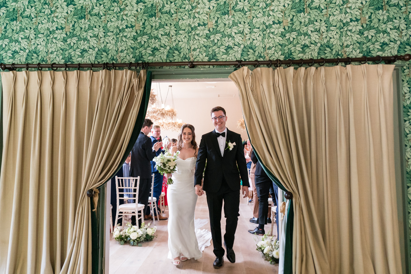 A colour image of a bride and groom leaving their wedding ceremony at Hampton Manor UK.