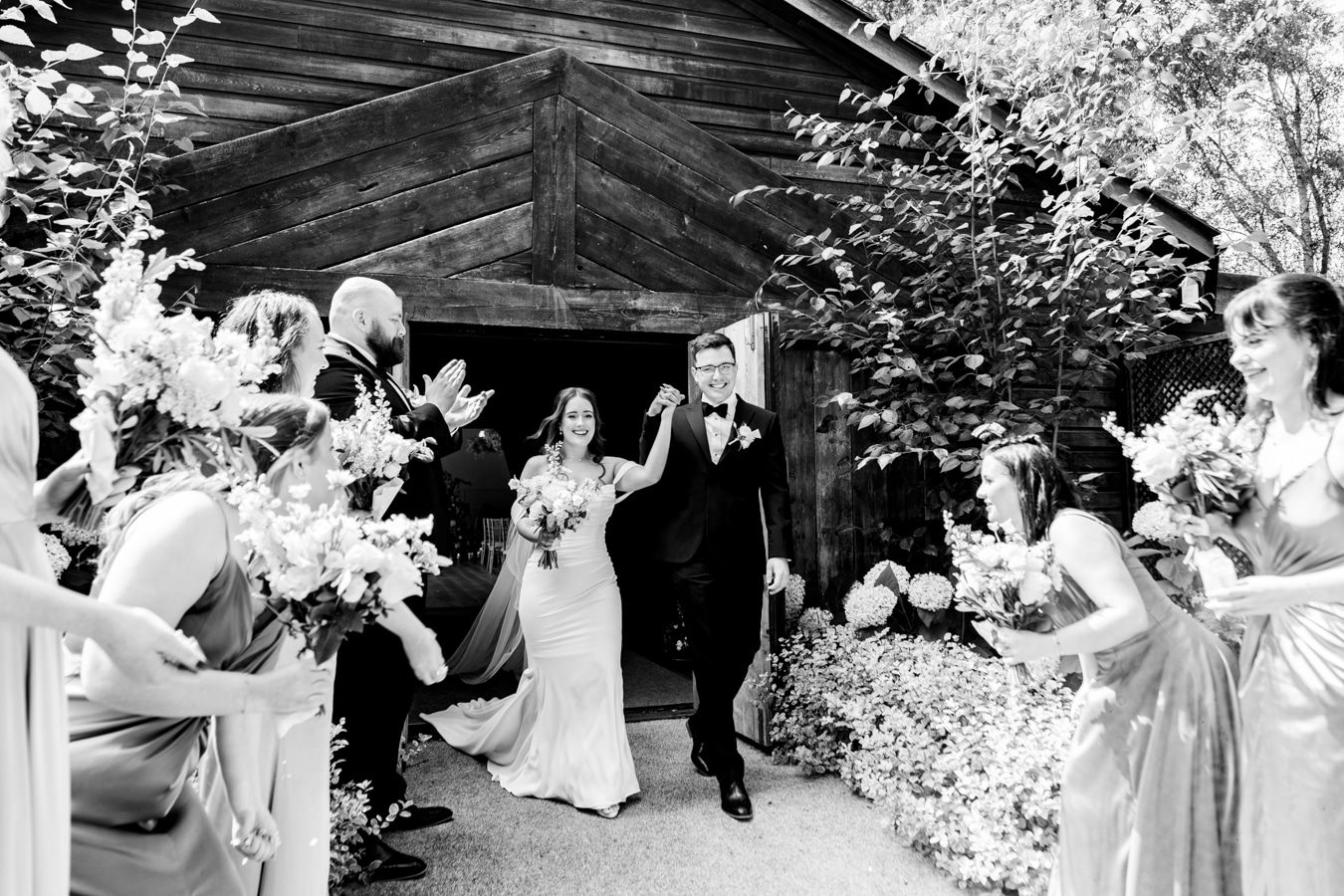A clack and white image of a bride and groom leaving their wedding ceremony at Hampton Manor wedding venue UK.