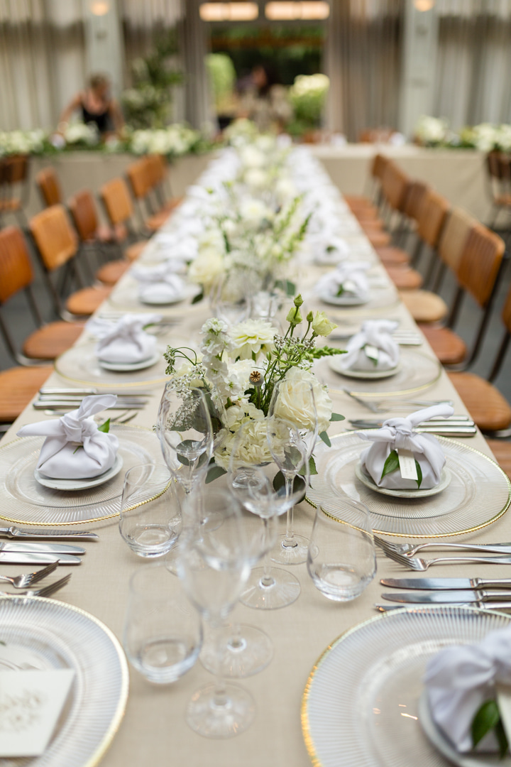 A colour image of a long wedding table with fresh white flowers styled by UK wedding Planner Soiree Studio for a Hampton Manor wedding.