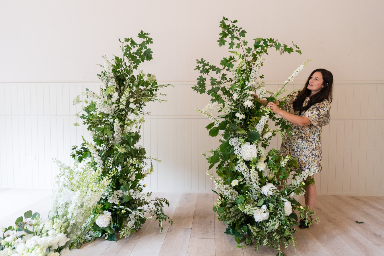 A colour image of a broken arch of flowers begin prepared for a wedding at Hampton Manor UK