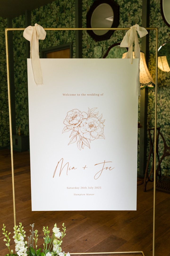 A colour image of a wedding welcome sign at Hampton Manor by Soiree Studio wedding planner UK.