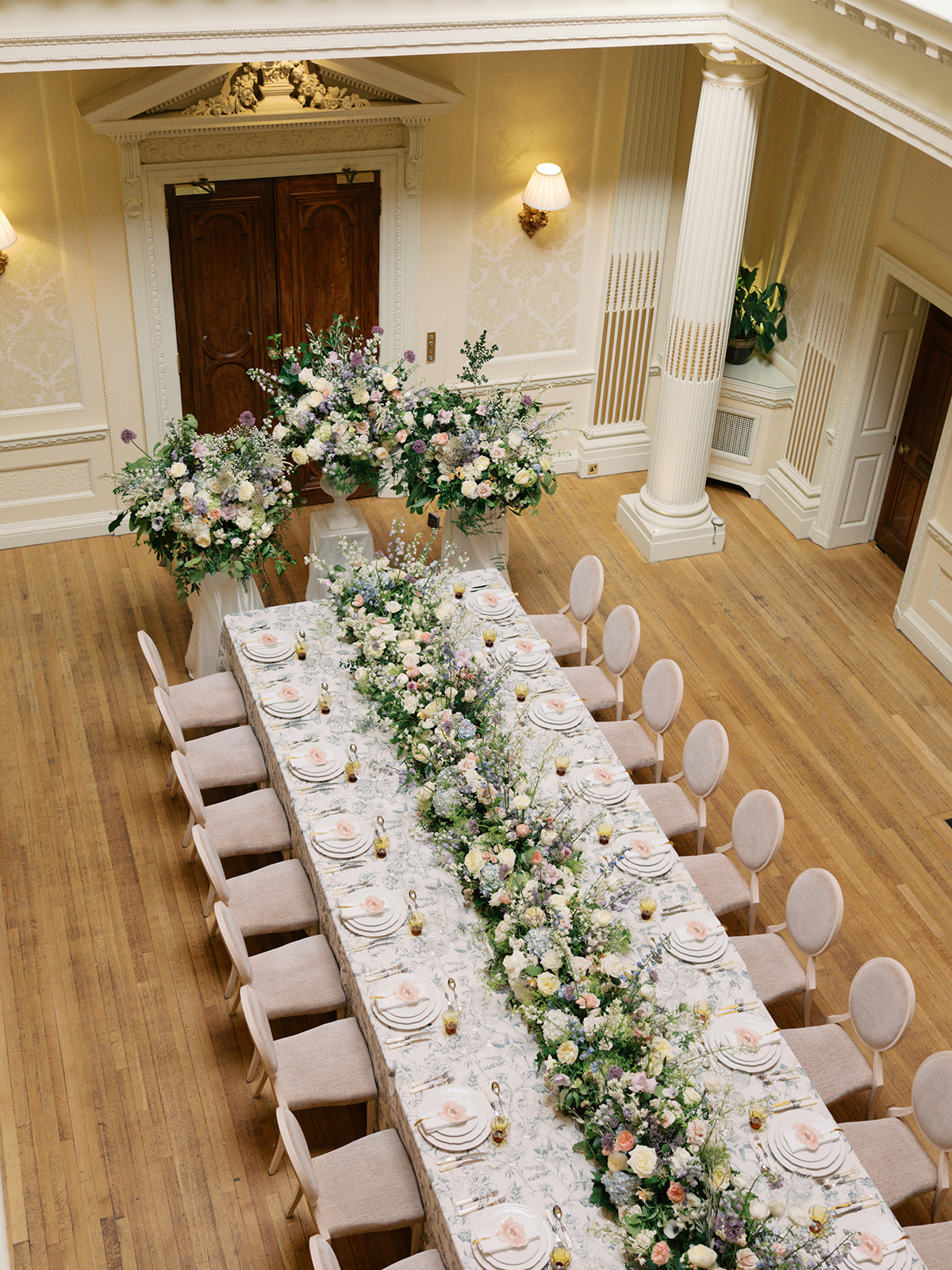 A black and white image of a wedding ceremony with huge floral backdrop at Palé Hall in Wales. Planned by Soirée Studio.